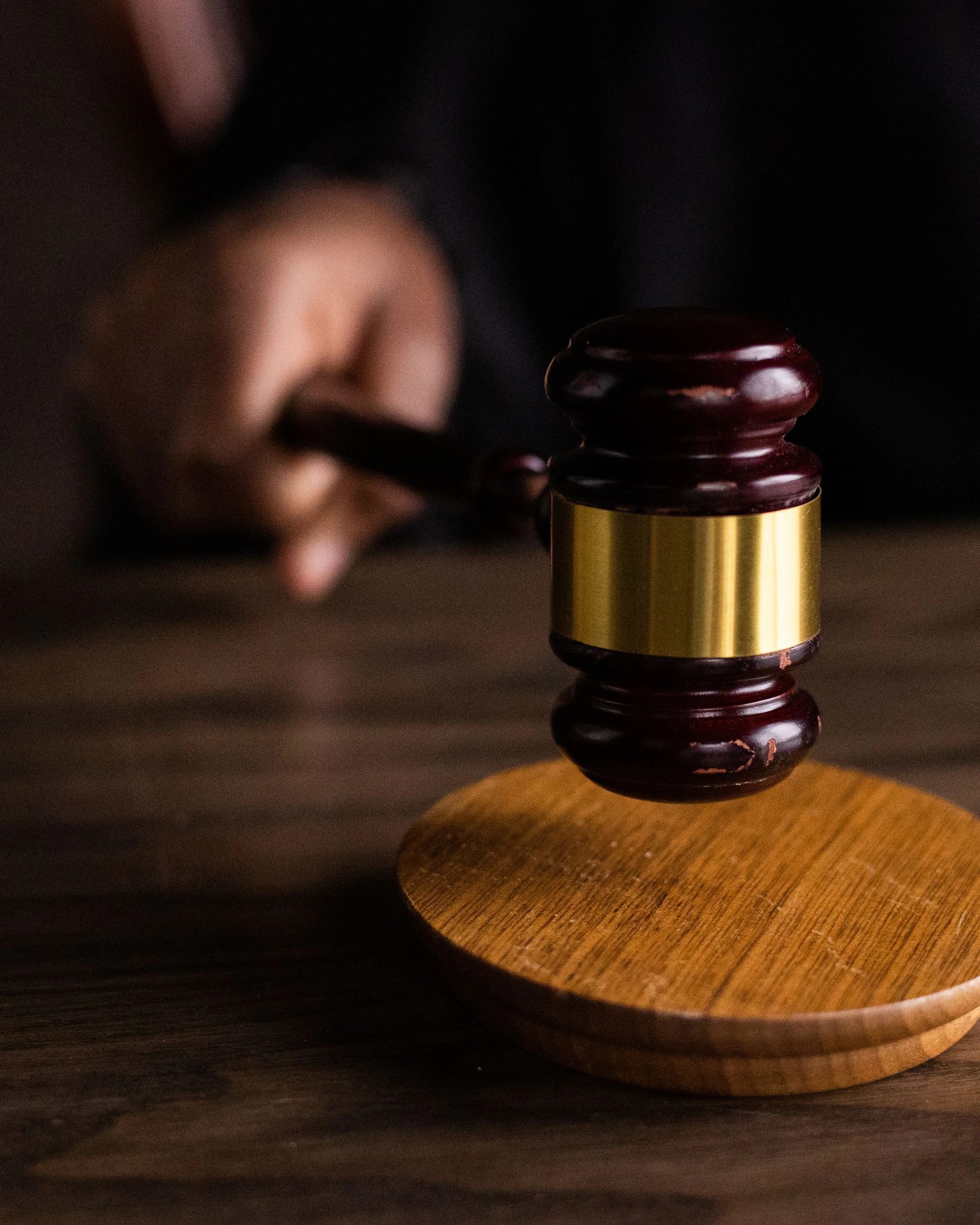 A hand bringing a gavel down in low light
