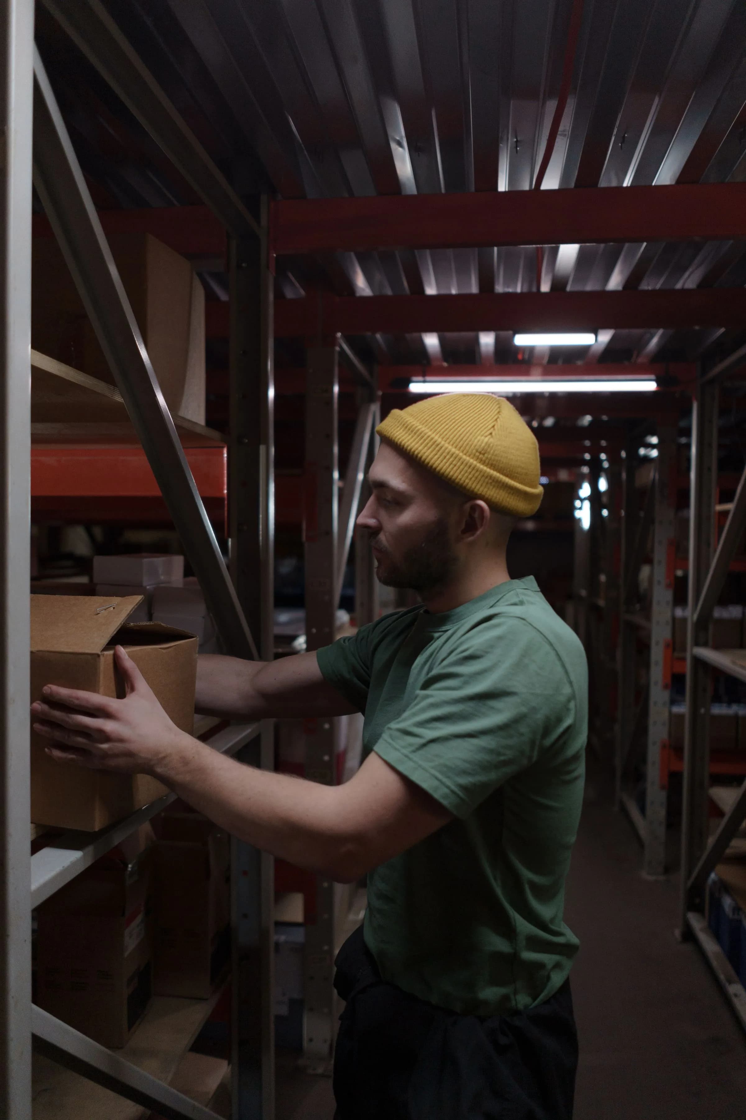 A warehouse associate handling a shipping box between shelves